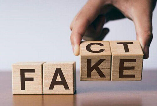 людина складає з кубиків слово: fact або fake