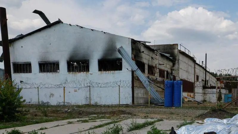 Ангар, де перебували азовці, після вибухів. Поруч з ним лежать тіла загиблих українських військових, 29 липня 2022 року, Оленівська тюрма