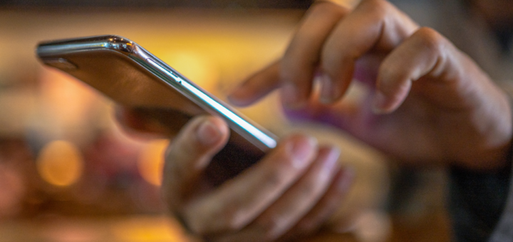 людина щось набирає на телефоні
