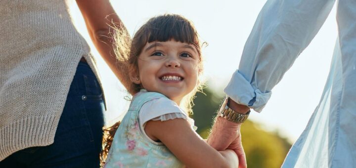 дівчинка тримає батьків за руки та всміхається