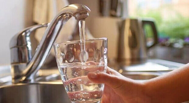 людина набирає воду в стакан з крану