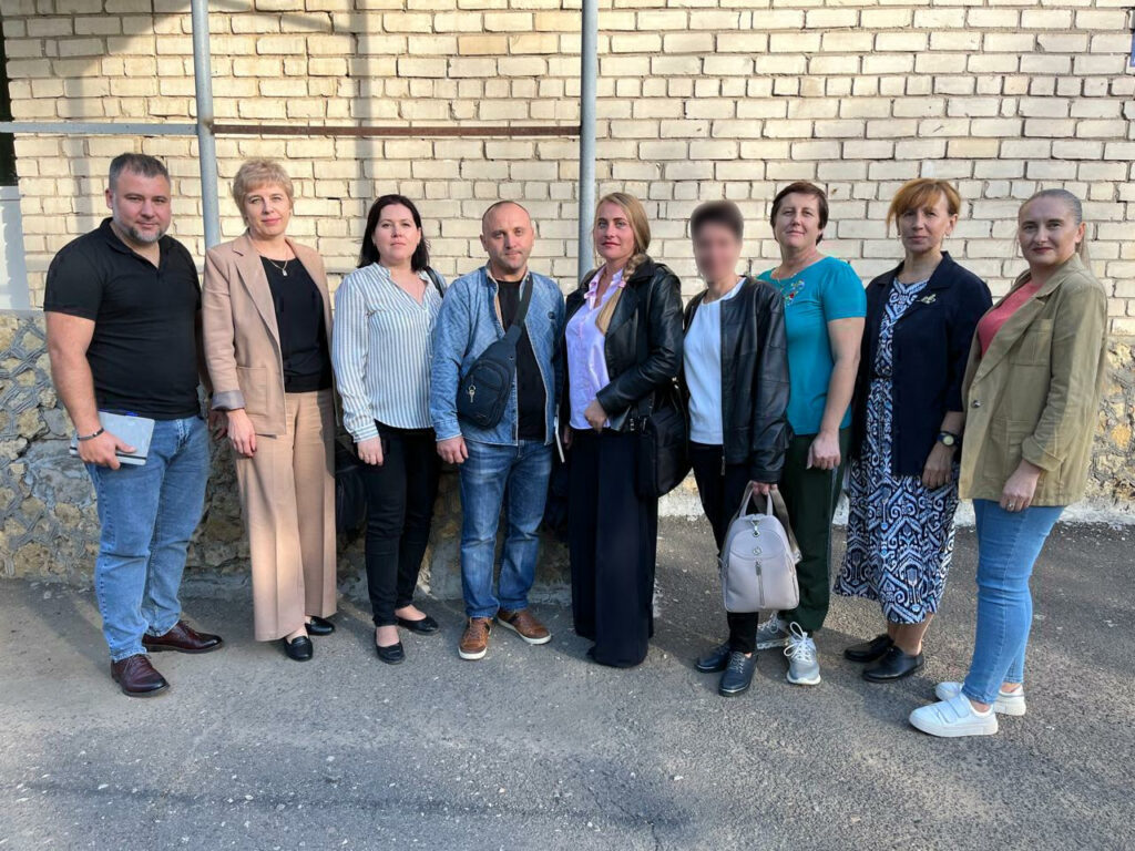 Біля цегляної стіни стоїть багато людей - учасники семінару з питань ветеранської політики