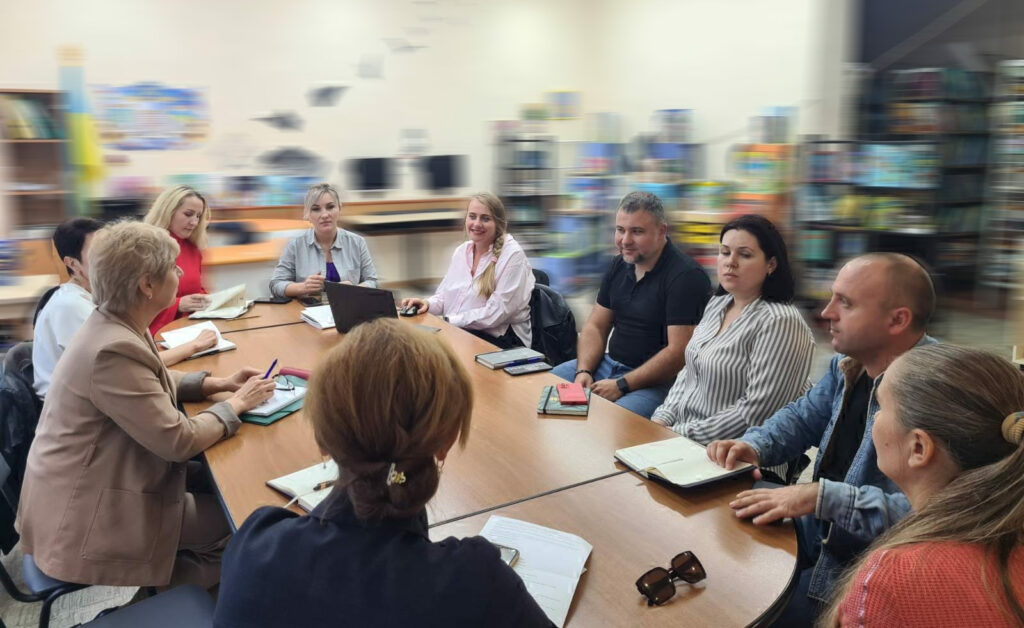 за довгим овальним столом сидять багато людей — учасників семінару з питань ветеранської політики