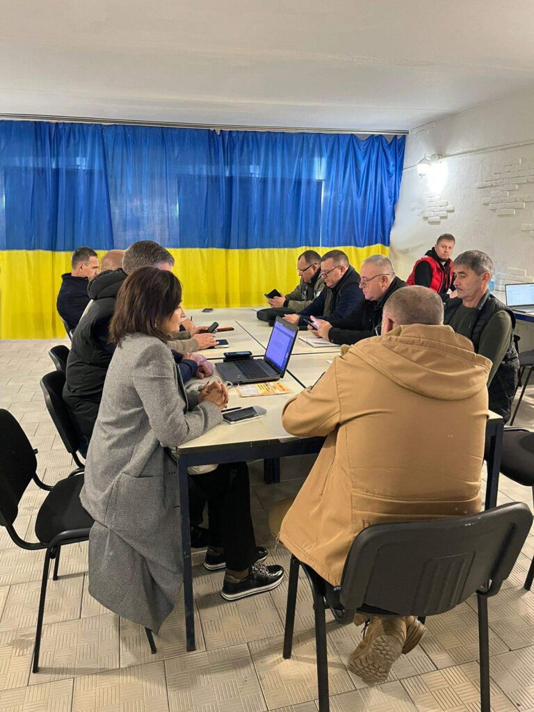 У бомбосховищі відбувається засідання робочої групи "Прозорість та підзвітність". Позаду учасників — великий прапор України