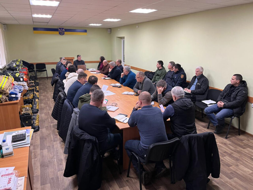 У великій світлій кімнаті за довгим столом сидять учасники наради -семінару