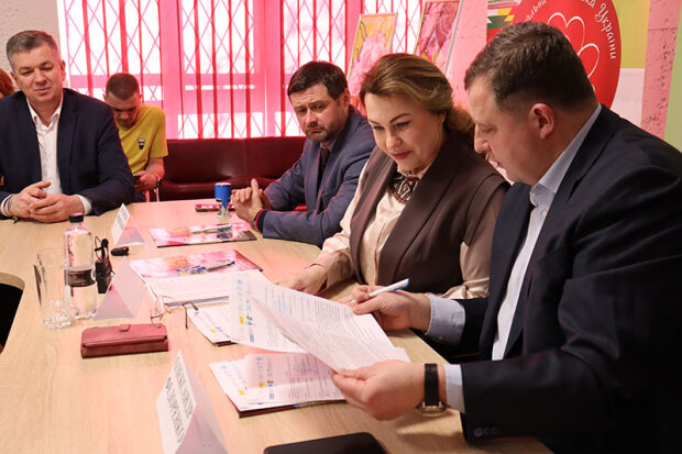 учасники пресконференції за столом переглядають документи