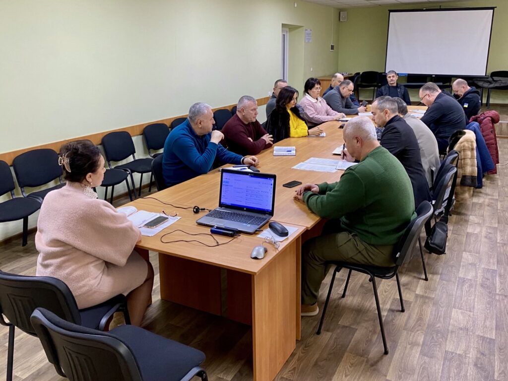 Начальники військових адміністрацій населених пунктів Херсонського району сидять у світлій кімнаті за довгим столом