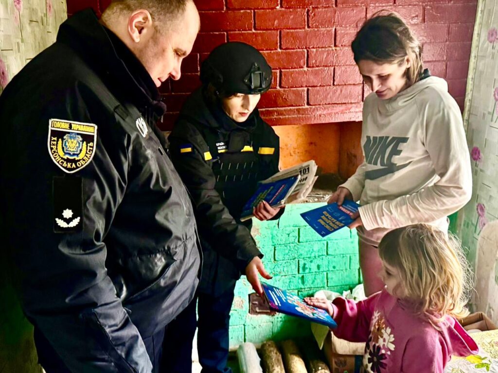 Працівники поліції дають дитині інформаційні буклети з безепеки, поруч у кімнаті стоїть її мати