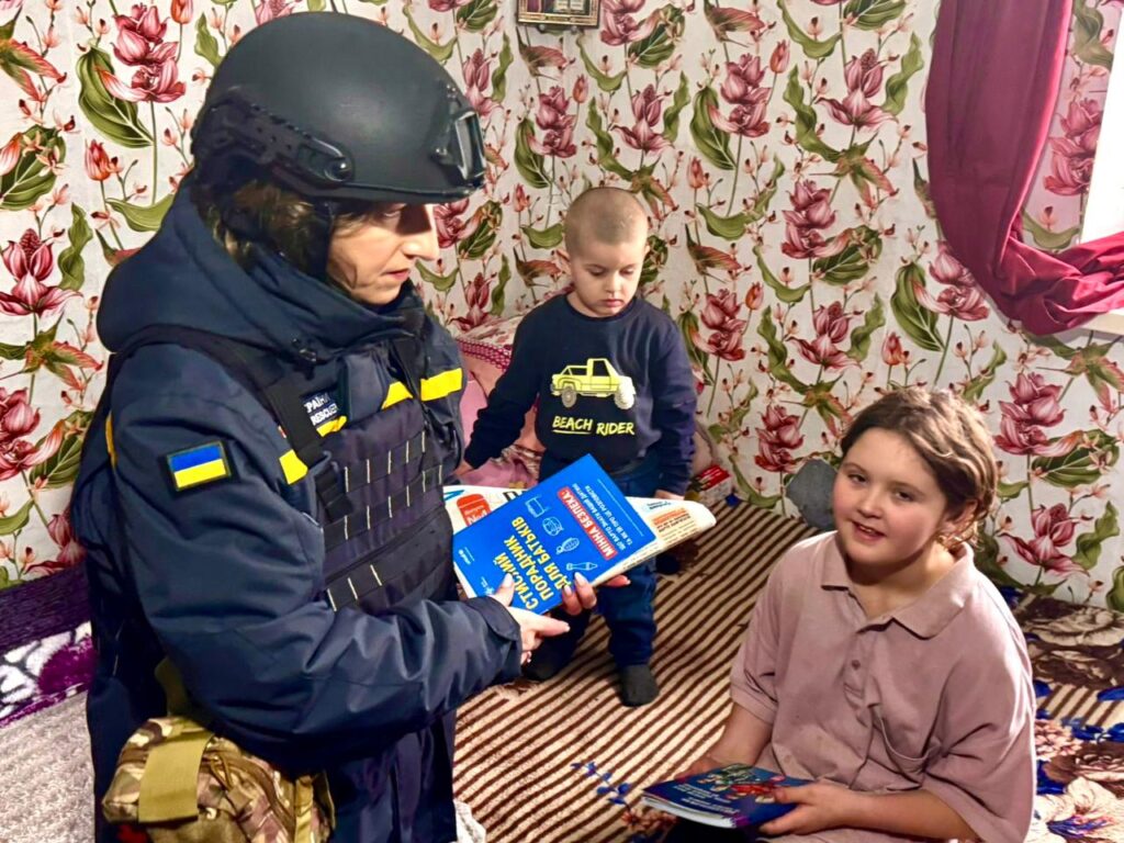 Працівниця поліції розповідає двом маленьким діткам в кімнаті про небезпеку від гри з вогнем