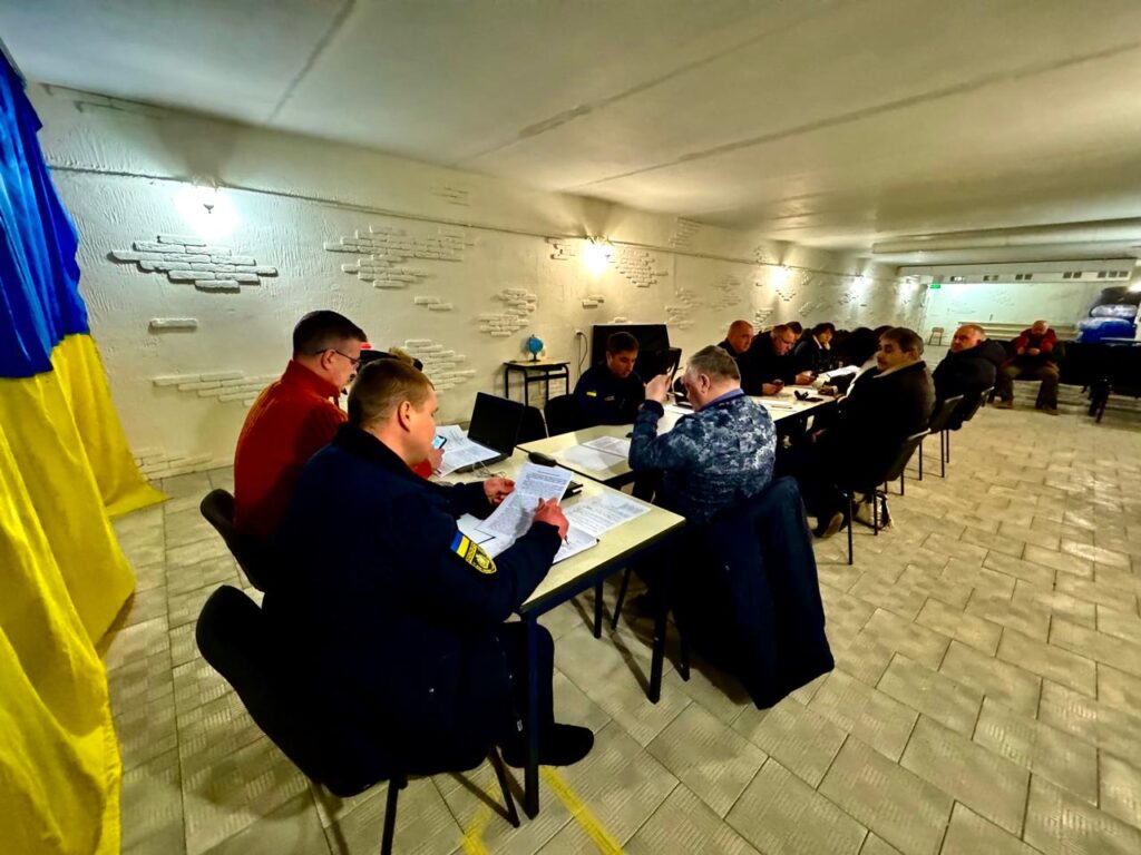 У підвальному кабінеті з білими стінами за великим довгим столом сидять члени комісії з ТЕБ та НС, в голові столу - М.Линецький та Р.Харченко