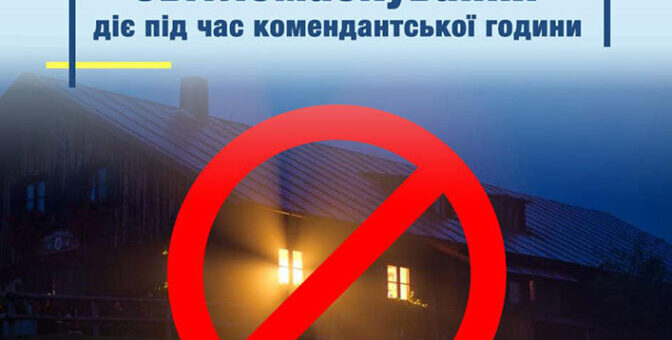 На зображенні будинок із увімкненим світлом у вікнах. Над зображенням розташоване велике червоне коло з діагональною лінією, що символізує заборону. У верхній частині фото є текст українською мовою: «Світломаскування діє під час комендантської години»