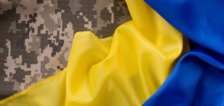 На зображенні показано камуфляжну тканину, частково накриту жовто-синім прапором. Камуфляжний візерунок складається з цифрового малюнка – поширеного у військовій формі. Жовто-синя тканина, що покриває камуфляж, нагадує прапор України
