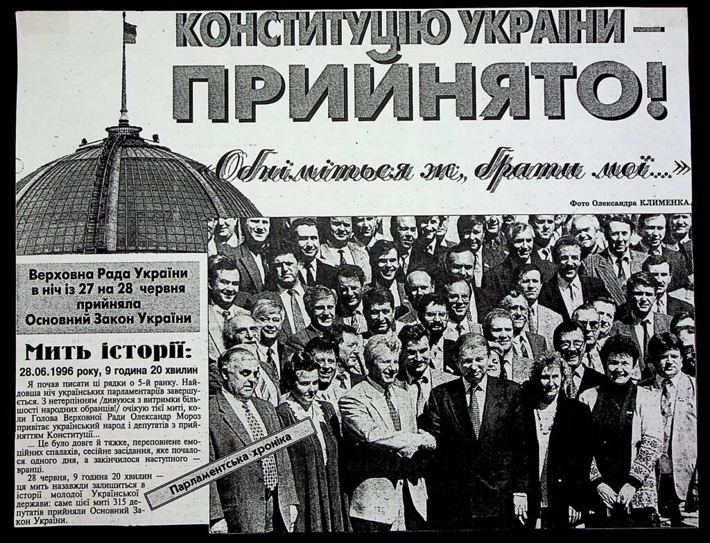 Історичний момент — депутати Верховної Ради святкують ухвалення Конституції України 28 червня 1996 року. Надпис: “Конституцію України — ПРИЙНЯТО!”, фраза “Обніміться ж, брати мої…”, тло — купол Верховної Ради