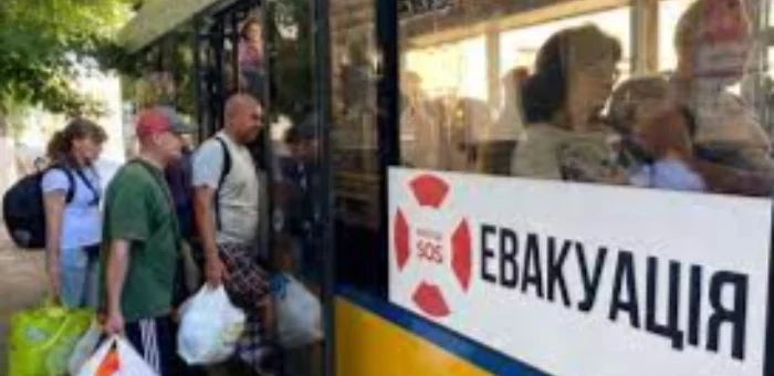 У жовтий автобус з написом "ЕВАКУАЦІЯ" сідають люди в літньому одязі