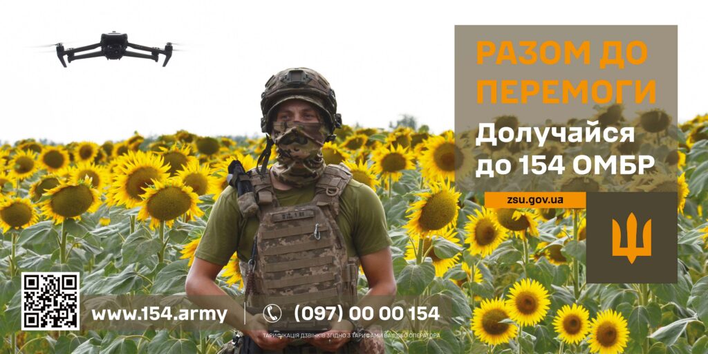 У полі соняшників стоїть військовослужбовець у повному камуфляжному спорядженні. Над ним у небі летить дрон. Праворуч на зображенні розміщено текст українською: «РАЗОМ ДО ПЕРЕМОГИ. Долучайся до 154 ОМБР. zsu.gov.ua». Унизу — вебсайт www.154.army, номер телефону (097) 00 00 154, QR-код і примітка про тарифікацію дзвінків. Атмосфера рішуча й мобілізаційна, з акцентом на природний пейзаж і технічну підготовку.