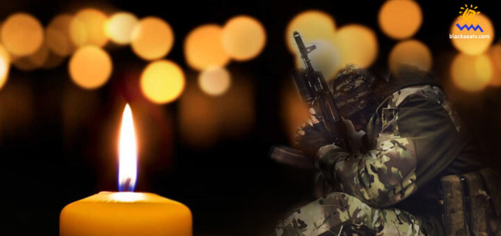 свічка пам'яті... позаду неї багато свічок і образ воїна, що сидить, притулившись до автомата