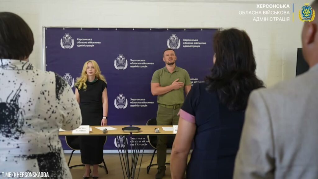 Мар'яна Томин та Олександр Прокудін тримають руку на серці під час виконання Гімну України