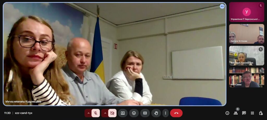 Скріншот відеозустрічі в Google Meet: троє учасників сидять разом у кімнаті з прапором України та фоном із пшеничним полем, ще троє — підключені дистанційно.