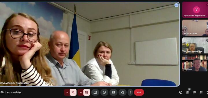 Скріншот відеозустрічі в Google Meet: троє учасників сидять разом у кімнаті з прапором України та фоном із пшеничним полем, ще троє — підключені дистанційно.