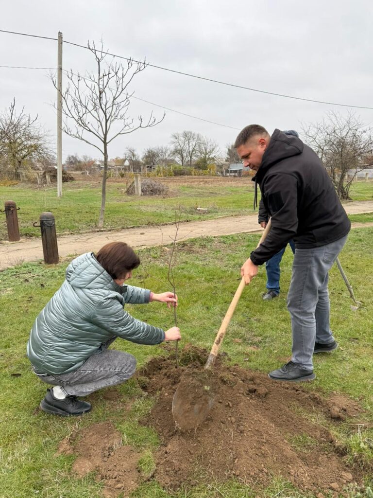 Дмитро Юнусов  та жінка у світлій куртці саджають дерево