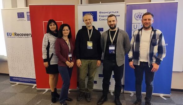 П’ятеро людей стоять у приміщенні перед трьома банерами. Лівий — «EU4Recovery» з логотипами ЄС і ПРООН. Центральний — напис «Фінансується Європейським Союзом». Правий — логотип ПРООН і текст українською.