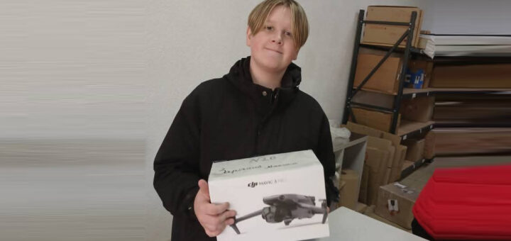 У приміщенні стоїть людина з коробкою дрона DJI Mavic 3. На коробці — зображення дрона та напис «DJI MAVIC 3». Зверху — рукописний напис: «N20» і «Зручний дрончик». Позаду — полиці з картонними коробками та пакувальними матеріалами, що нагадує склад або зону зберігання.