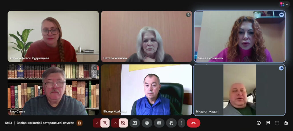 Скріншот онлайн-зустрічі з шістьма учасниками. Серед них: Кудрявцева — на фоні рослини, Наталя Устінова — біля дерев’яної панелі, Олена Кириченко — на фоні бежевої стіни з полицею, Ігор Савва — перед книжковою шафою, Віктор Колісник — в офісі з жовтим прапором, Михайло Жадан — у салоні авто. Час — 10:33, назва зустрічі — «Засідання комісії ветеранської служби».