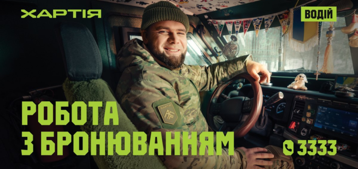 Військовий у камуфляжі сидить за кермом машини, усміхається, на панелі іграшка-собака та прикраси, текст українською: “Хартія. Водій. Робота з бронюванням. 📞 3333