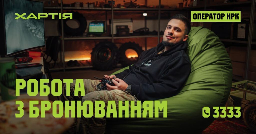 Чоловік сидить на зеленому пуфі з геймпадом у руках, перед ним монітор, поруч піца, текст українською: “Хартія. Оператор НРК. Робота з бронюванням. 📞 3333