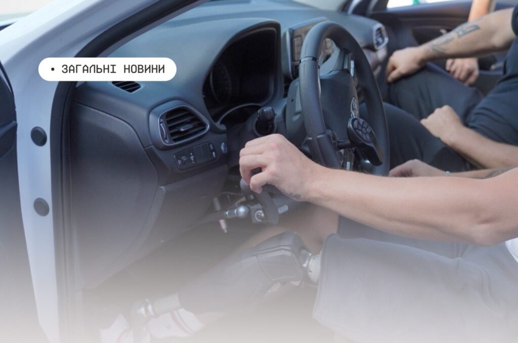 Інтер’єр автомобіля: водій із протезом ноги керує машиною за допомогою ручних пристроїв, поруч сидить пасажир