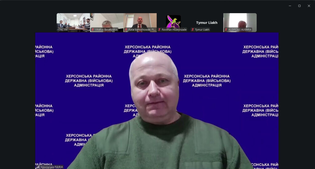 На екрані Михайло Жадан у зеленій сорочці сидить перед синім фоном із написом «Херсонська районна державна (військова) адміністрація». У верхній частині — маленькі віконця інших учасників із іменами «Vitalius Besakirskas», «Rafal Bartochowski, PL», «Rovshan Huseynzade» тощо. 