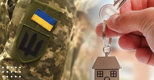 Камуфляжна форма з нашивками прапора України та тризуба, поруч рука з ключем і брелоком у формі будинку