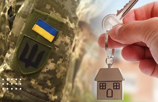 Камуфляжна форма з нашивками прапора України та тризуба, поруч рука з ключем і брелоком у формі будинку