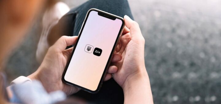 Людина тримає смартфон із логотипом застосунку Дія на екрані з градієнтним фоном