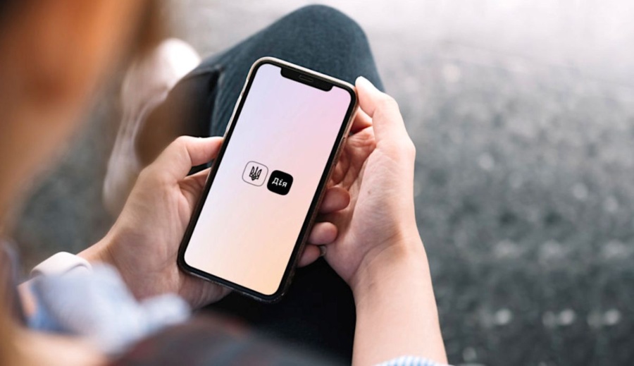 Людина тримає смартфон із логотипом застосунку Дія на екрані з градієнтним фоном