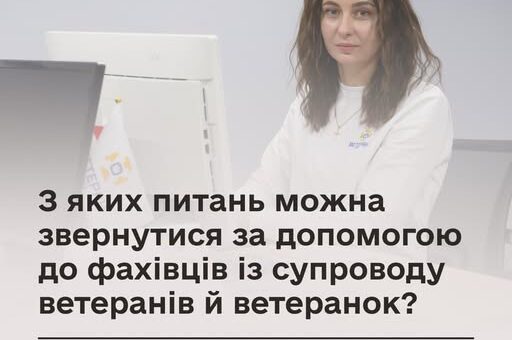 Людина сидить за столом перед комп’ютером, на екрані текст про допомогу ветеранам