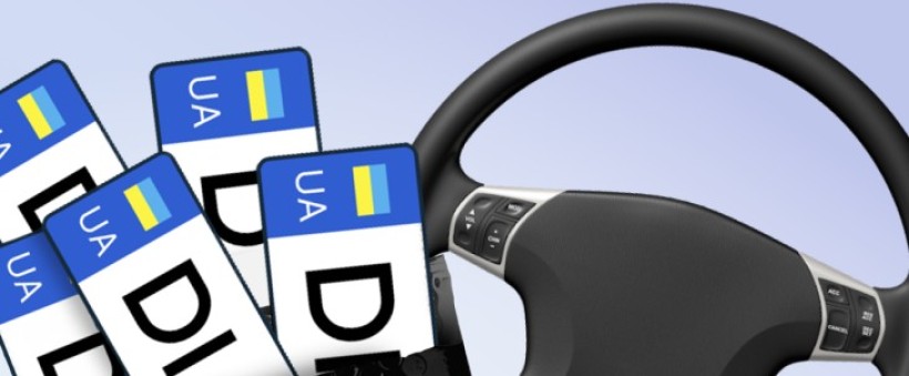 Кермо автомобіля праворуч, ліворуч кілька українських номерних знаків із позначкою UA та літерами DL