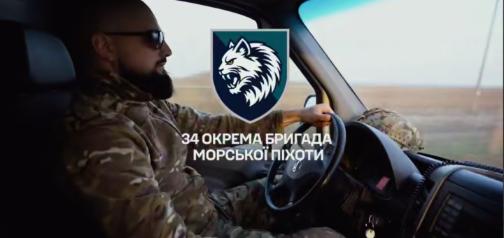 Військовий у камуфляжі та окулярах керує автомобілем, на зображенні емблема вовка й текст про 34-ту окрему бригаду морської піхоти