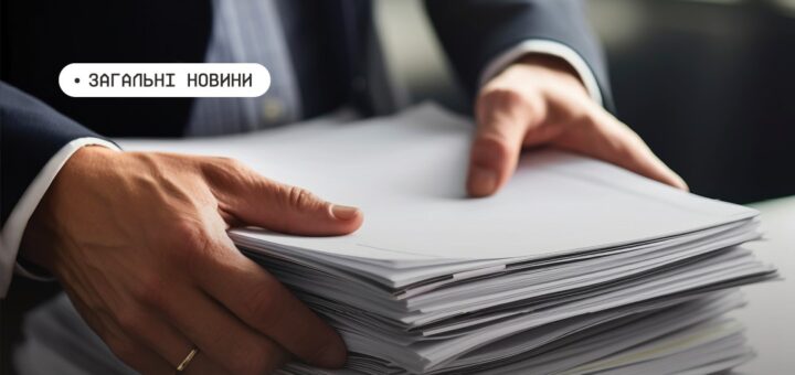 Людина в костюмі переглядає та впорядковує велику стопку документів на столі; текст “Загальні новини