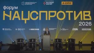 Сцена з великим банером «Форум Нацспротив 2026». На трибуні виступає промовець. Освітлення синьо-жовтими променями, на фоні — логотипи організацій.