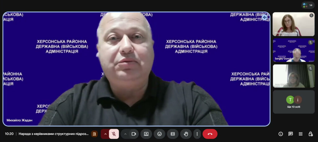 Скріншот відеоконференції. У центрі — Михайло Жадан на синьому фоні з написом «Херсонська районна державна (військова) адміністрація». Праворуч — інші учасники, позначено ще 10 осіб. Внизу — час «10:20» та назва зустрічі «Нарада з керівниками структурних підрозділів».