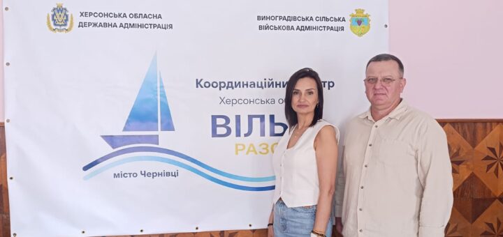 Тетяна Гасаненко та Валерій Мельниченко на фоні плакату «Вільні разом» у місті Чернівці