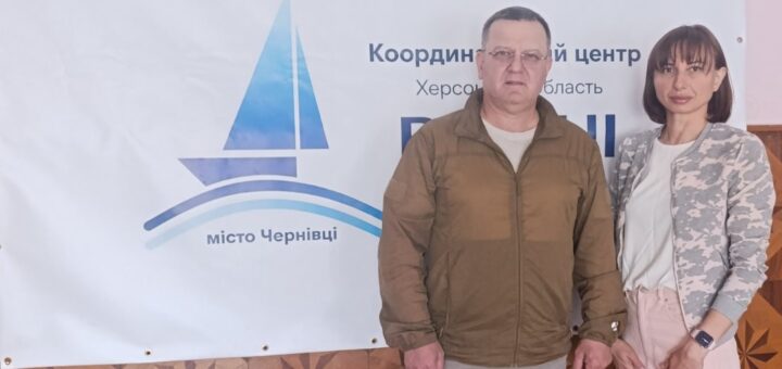 Начальник Служби у справах дітей Херсонської районної державної адміністрації Євгенія Степанська та начальника Виноградівської сільської військової адміністрації Валерій Мельниченко під час робочої зустрічі, стоять біля плакату «Вільні разом» у місті Чернівці