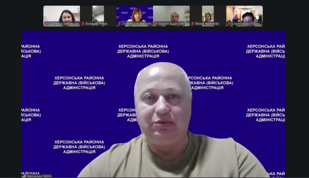Скріншот відеоконференції. У центрі — учасник на синьому фоні з білим написом «Херсонська районна державна (військова) адміністрація». Угорі — маленькі вікна з іншими учасниками.