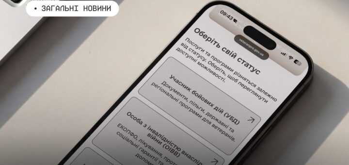 Смартфон на світлій поверхні поруч із клавіатурою ноутбука; на екрані сторінка “Оберіть свій статус” із трьома категоріями підтримки для ветеранів та їхніх родин