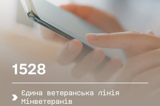 Крупний план рук із телефоном, тло розмите. На екрані — текст українською: «Єдина ветеранська лінія Мінветеранів — 1528»
