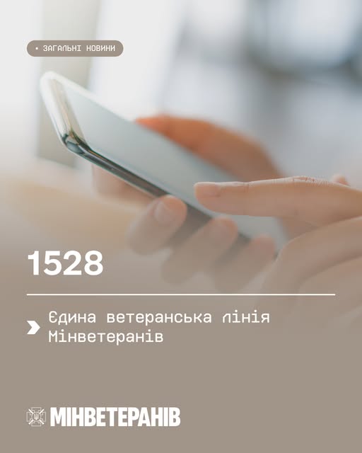 Крупний план рук із телефоном, тло розмите. На екрані — текст українською: «Єдина ветеранська лінія Мінветеранів — 1528»
