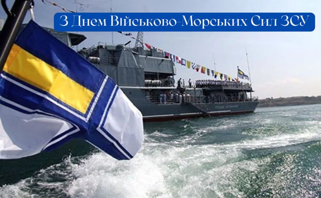 Український військовий корабель рухається морем, прикрашений сигнальними прапорами. На передньому плані — військово-морський прапор із синім хрестом та жовтою смугою. На палубі стоять моряки у строю. Текст на зображенні: «З Днем Військово-Морських Сил ЗСУ»