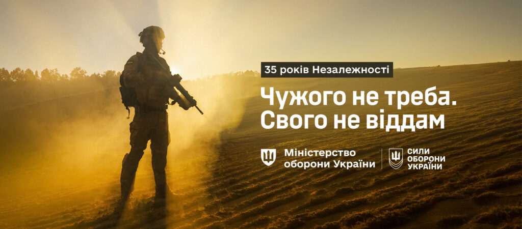 Солдат стоїть на запиленому полі на тлі заходу чи сходу сонця, тримаючи зброю. Позаду — лінія дерев і золотаве небо, що створює драматичну й патріотичну атмосферу. Текст: «35 років Незалежності. Чужого не треба. Свого не віддам. Міністерство оборони України | Сили оборони України».