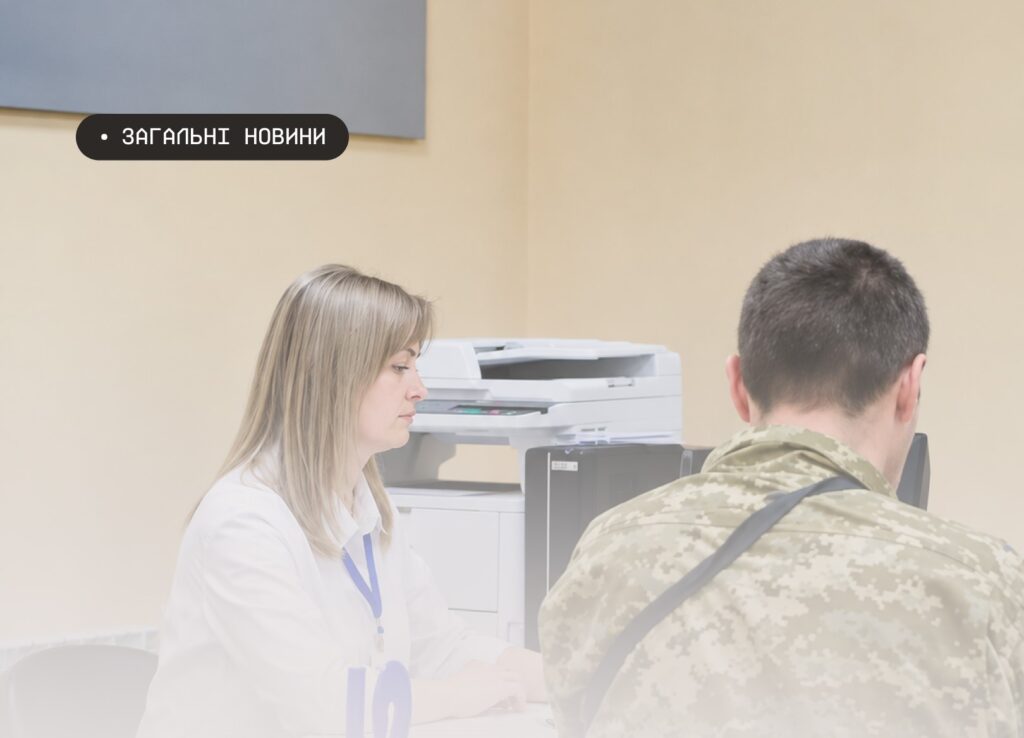 Інформаційне фото: двоє людей сидять за столом у кабінеті; один у білій сорочці з синім бейджем, інший — у камуфляжній формі; позаду видно принтер; текст — “ЗАГАЛЬНІ НОВИНИ”.